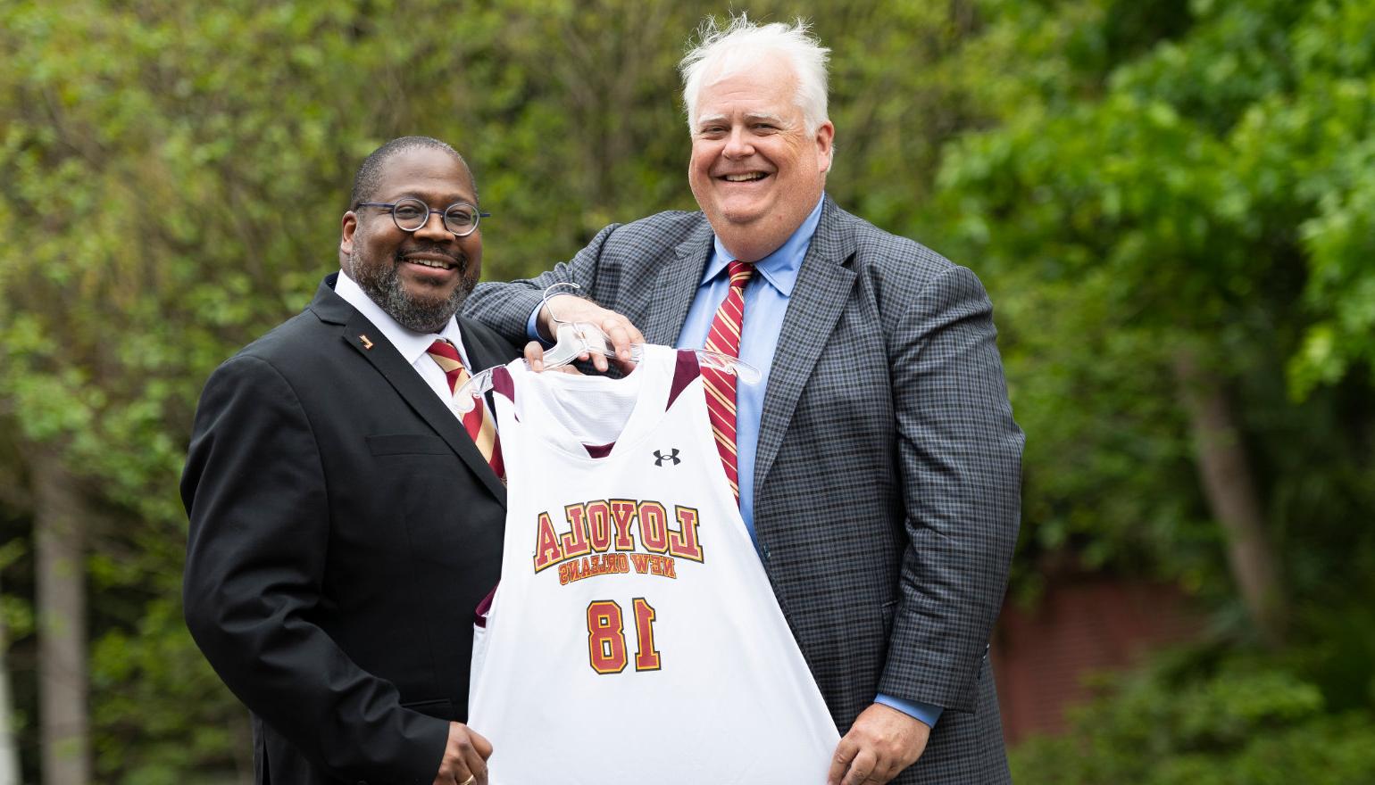 Stephen L和ry '83, chair of the 校董会, presents Dr. Xavier 科尔 with a #18 basketball jersey